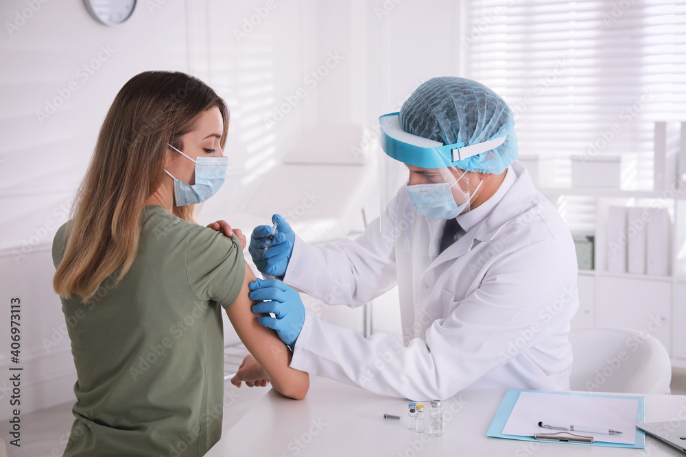 Doctor vaccinating young woman against Covid-19 in clinic Doctor vaccinating young woman against Covid-19 in clinic