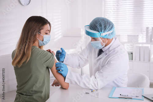Fototapeta Naklejka Na Ścianę i Meble -  Doctor vaccinating young woman against Covid-19 in clinic