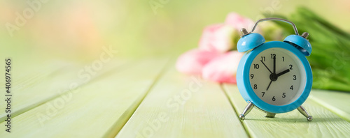 Spring time daylight saving concept - with alarm clock and flowers, copy space photo