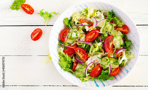 Fresh tomatoes with cucumber, lettuce, red onion and spices in a white bowl.  Concept healthy appetizer. White wooden background. Top view, overhead, copy space