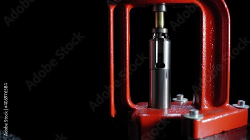 The process of making a rifle cartridge. Hand press and ammo shell against dark background, soft focus. Copy space