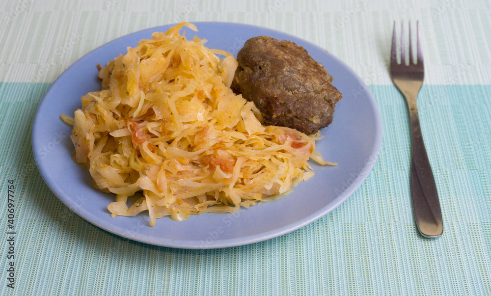 Stewed white cabbage with a cutlet steak on a plate. A dish of Russian, Polish cuisine. Garnish in the USSR. Stewed white cabbage with a cutlet steak on a plate. A dish of Russian, Polish cuisine. Garnish in the USSR.
