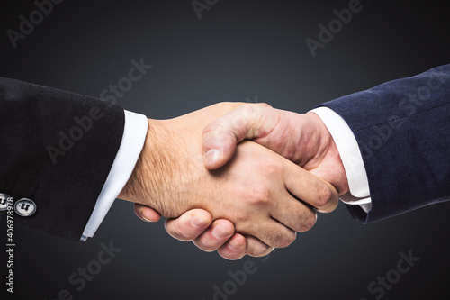 Handshake of two businessmen on a black wall background, partnership concept, close up