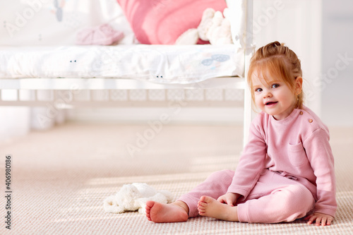 cute toddler baby girl sitting on the carpet in the nursery room