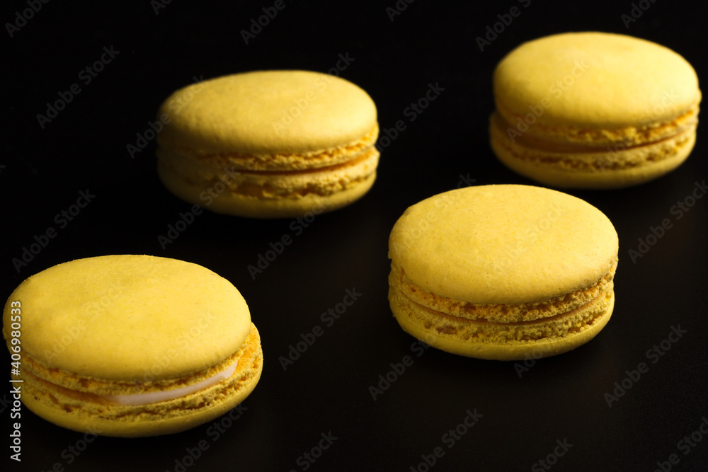 French cookies. Yellow macaroons isolated on a dark, black background. almond cookies. French cookies. Yellow macaroons isolated on a dark, black background. almond cookies.