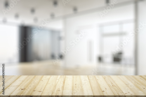 Empty wooden table top with light sunny furnished office on background, mock up