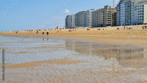 Beach with sand, houses, people, and hotel in the evening.