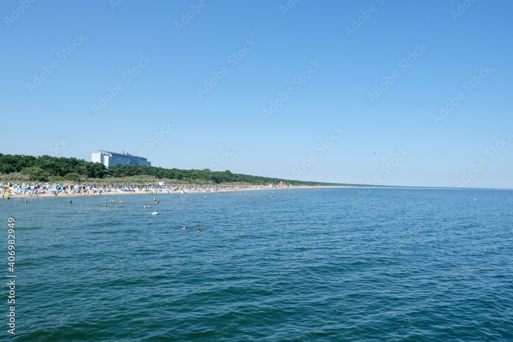 Fototapeta premium The beach of Zinnowitz with many beach chairs and a hotel on a sunny day in summer.