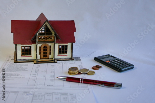 Toyhouse, calculator, and coins on the table photo