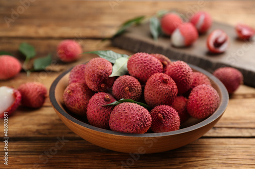 Fresh ripe lychee fruits in bowl on wooden table