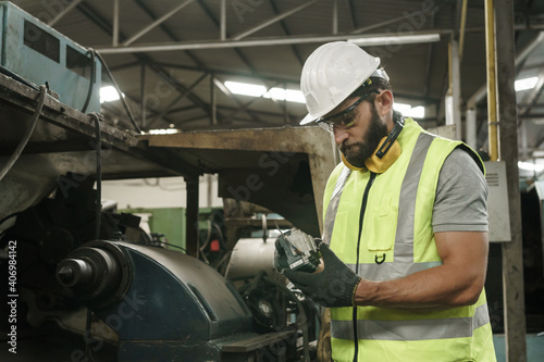 Engineer working at industrial machinery in factory. Manual workers cooperating while measuring a electronic.