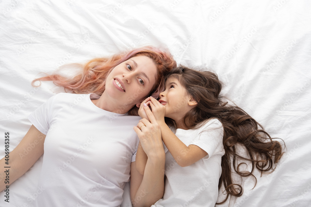 young mother and little active daughter lying in bed at home, having fun. young mother and little active daughter lying in bed at home, having fun.