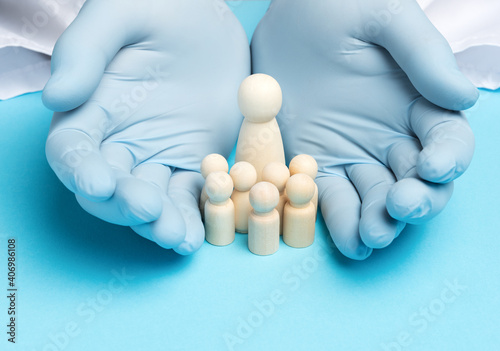 two male hands in blue latex gloves and wooden figurines of a woman with children