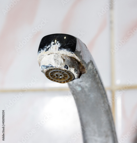 metal faucet in the bathroom with white deposits photo