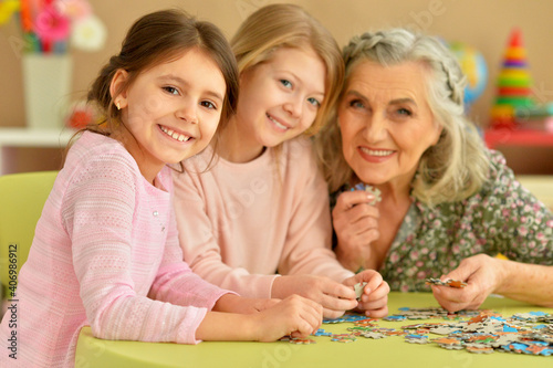 Grandmother with little granddaughters collecting puzzle