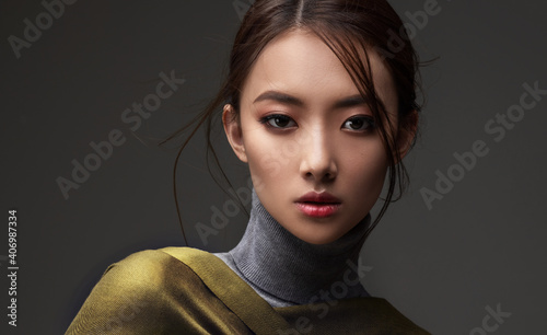 Beautiful Asian woman in a green shawl. Beauty of mysterious Chinese girl with flowing hair. Fashion, clothing and cosmetics