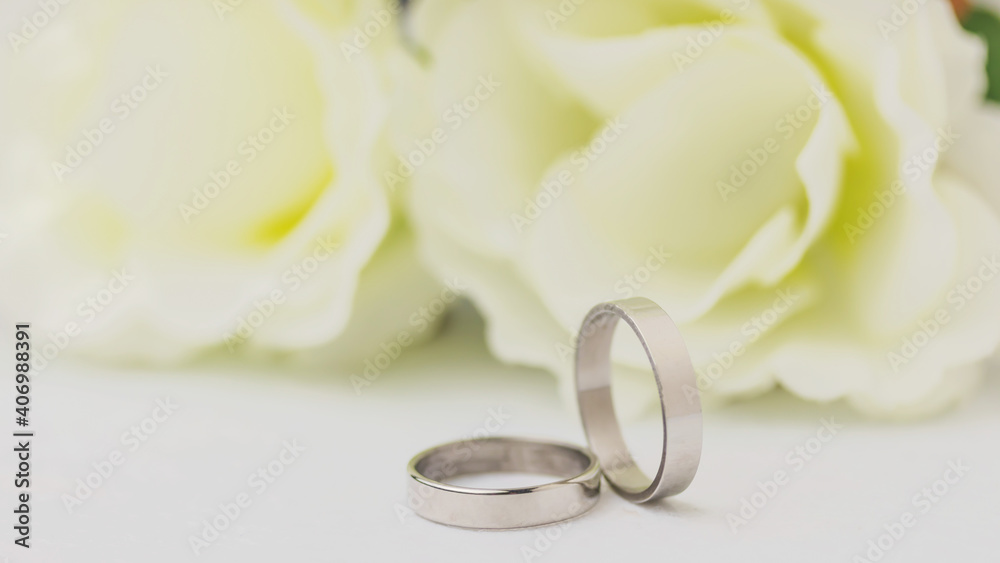 Wedding rings lie near a beautiful bouquet as bridal accessories.Wedding rings and roses bouquet.concept for a wedding card. Wedding rings lie near a beautiful bouquet as bridal accessories.Wedding rings and roses bouquet.concept for a wedding card.