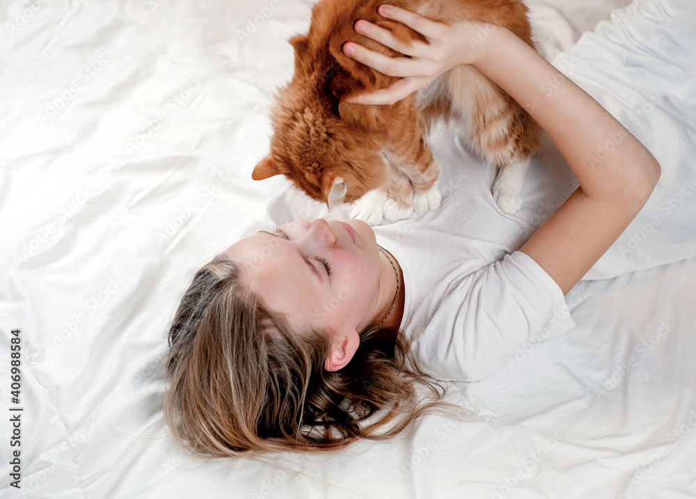 Teen girl relaxing in the bed with her cat, close-up. Friendship between kids and animals Teen girl relaxing in the bed with her cat, close-up. Friendship between kids and animals