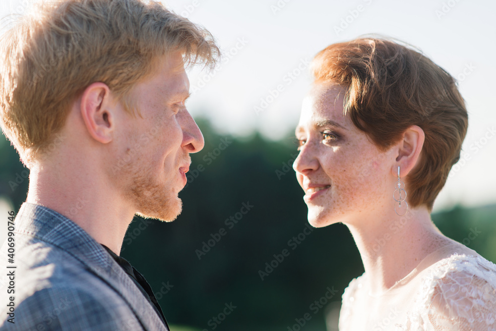 Nice redhead young just married happy couple kissing in the sunset outdoors Nice redhead young just married happy couple kissing in the sunset outdoors