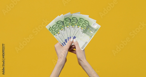 Female hands holding euro banknotes on a yellow background. Euro Money in woman hand. Euro cash background
