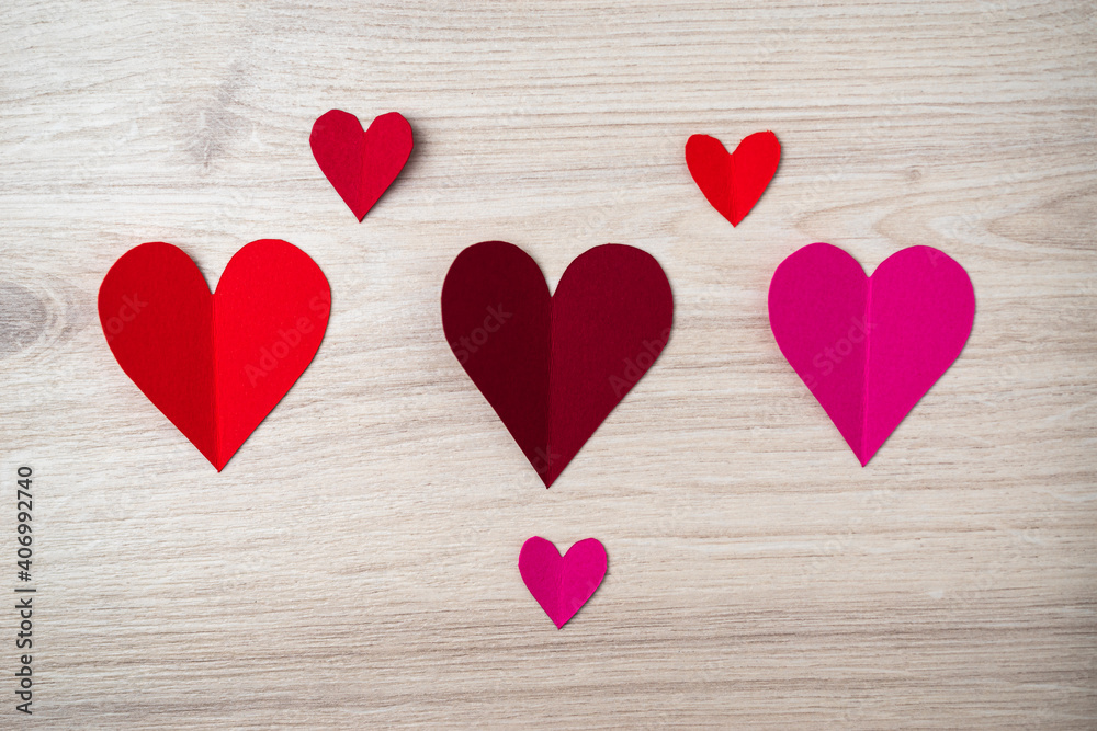 Cutted and folded paper Red hearts on a bright wooden Background. Card for Valentine's Day. Cutted and folded paper Red hearts on a bright wooden Background. Card for Valentine's Day.