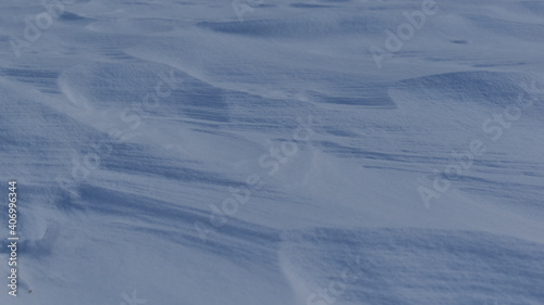 Vom Wind verwehte Schneeoberfläche mit Windstrukturen als winterlicher Hintergrund mit Naturschnee 