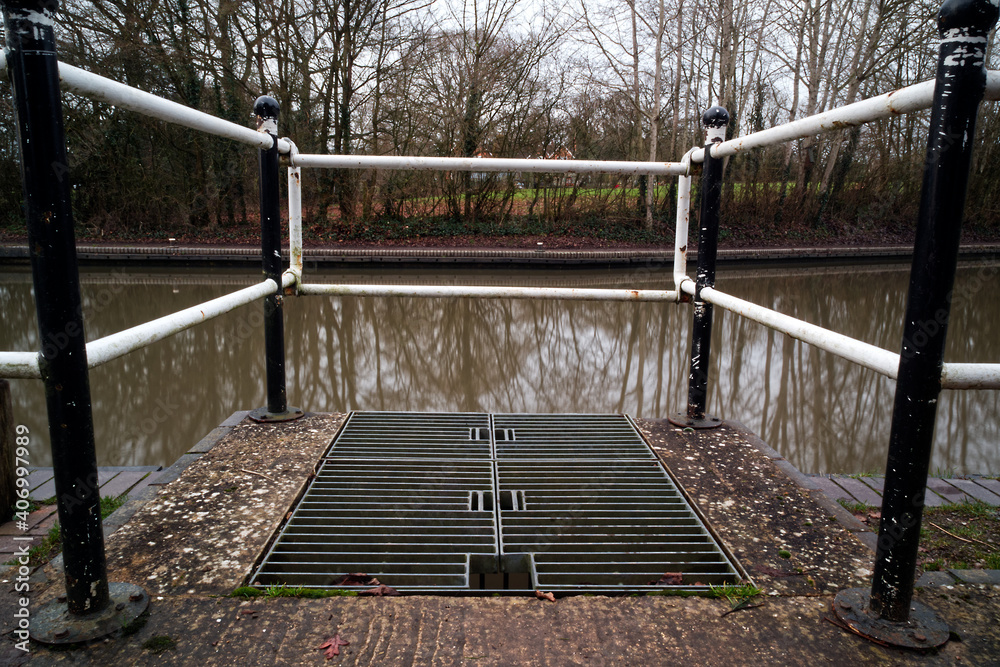 Metal grill and railing around a drain cover next to the canal Metal grill and railing around a drain cover next to the canal