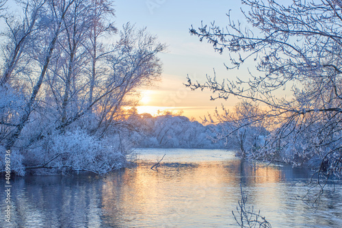 Winter sunset. River with all banks and frozen trees.