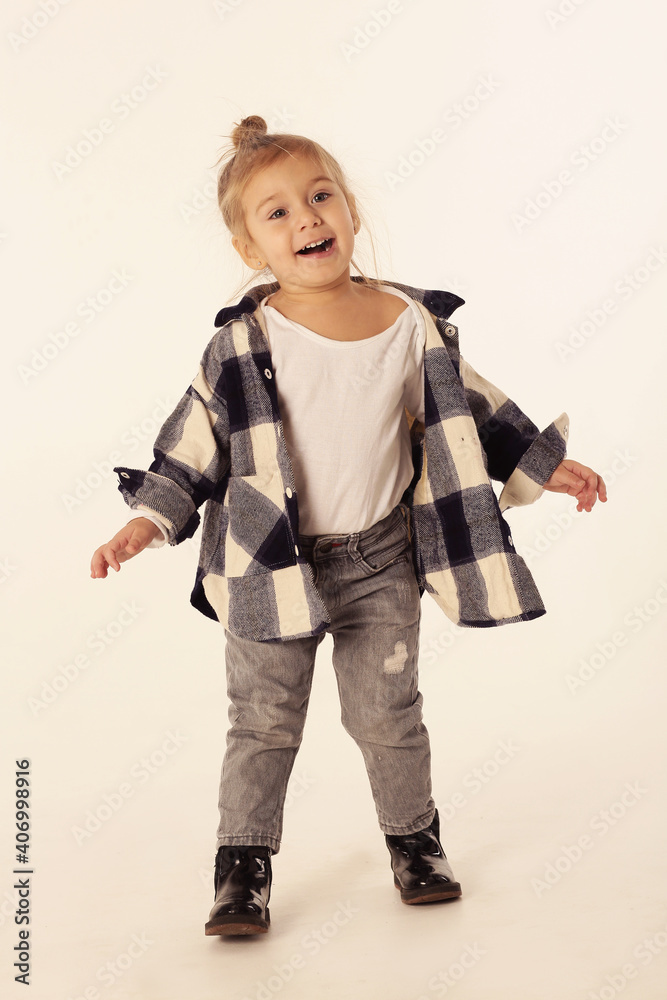 cute little blond baby girl in black boots, jeans, checkered shirt with copy space isolated on white cute little blond baby girl in black boots, jeans, checkered shirt with copy space isolated on white