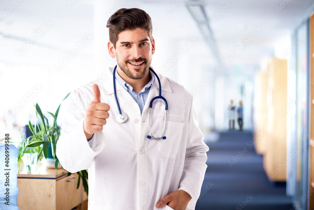 Happy male doctor giving thumbs up while looking at camera and smiling Happy male doctor giving thumbs up while looking at camera and smiling