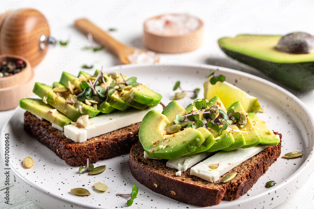 healthy toasts with avocado cheese and whole wheat rye bread on a plate. Delicious snacks and avocado sandwiches. Vegetarian food. Vegan menu. Food recipe background healthy toasts with avocado cheese and whole wheat rye bread on a plate. Delicious snacks and avocado sandwiches. Vegetarian food. Vegan menu. Food recipe background