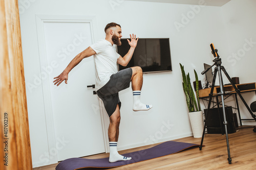 Young man making sport fitness exercises at home. Training during quarantine. Online training in front of the smartphone camera.