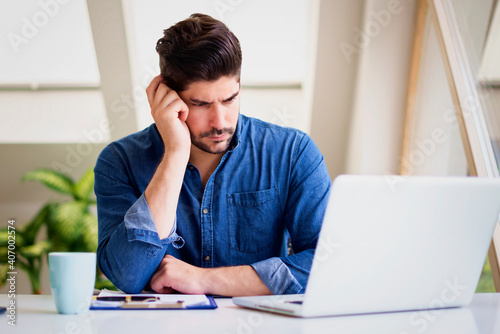 Businessman looking thoughtfully while working on laptop at home