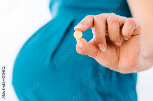 Pregnant woman holding pill in her hand
