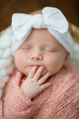 sleeping newborn girl in a white bow