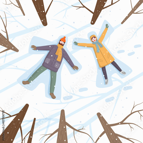 Happy couple of young people making snow angel in snow.