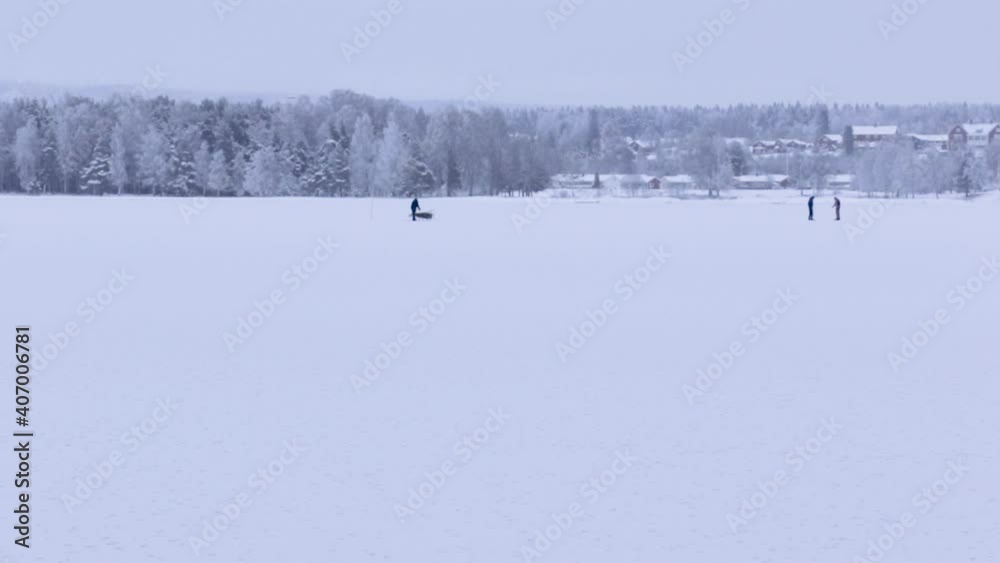 three people on a frozen lake including one person on a sled three people on a frozen lake including one person on a sled