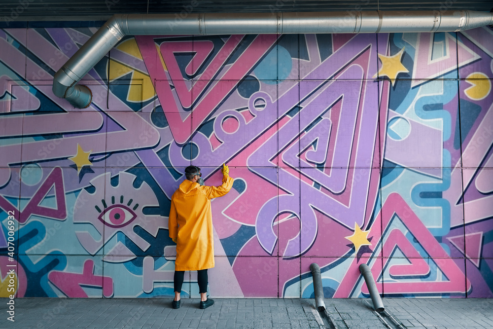 Naklejka premium Street artist painting colorful graffiti on wall