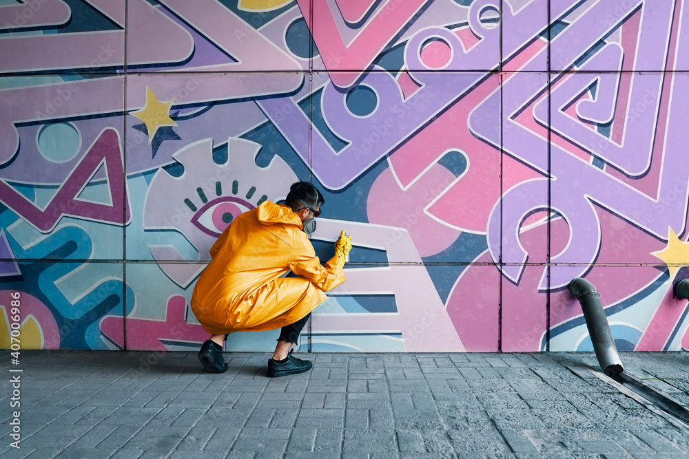 Fototapeta premium Street artist painting colorful graffiti on wall
