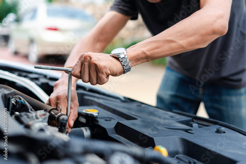 The male mechanic's hand holds the wrench In order to fix And check car engine, engineer concept and car repair
