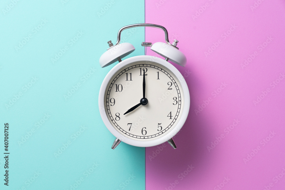 Retro alarm clock on pink and green table background, vintage lifestyle concept Retro alarm clock on pink and green table background, vintage lifestyle concept