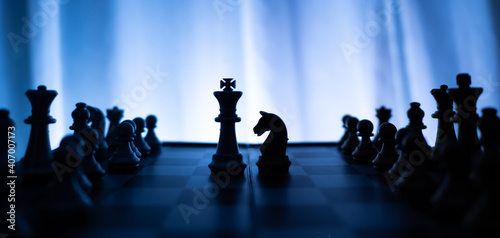 silhouette of King versus horses chess board game on cold color tone background