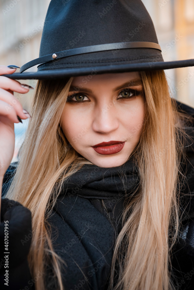 european young blonde woman in black clothes and hat close up