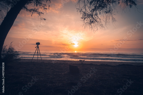 silhouette of smartphone on a tripod to capture the sunrise at the beach.