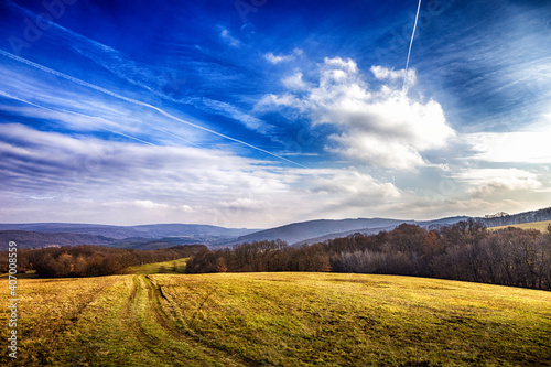 Schönes Feld mit blauem Himmel und weissen Wolken, Kondensstreifen im Winter oder im Herbst