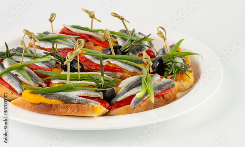 On a white background plate with canapes of anchovies and vegetables.