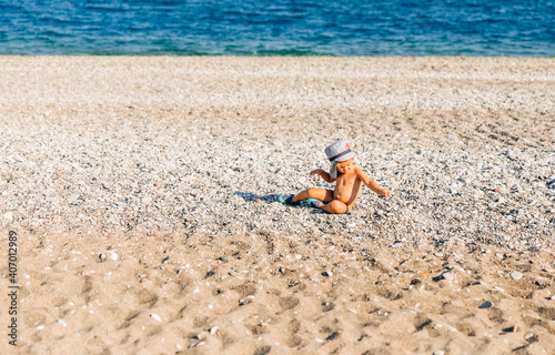 Lonely toddler girl sitting on beach
