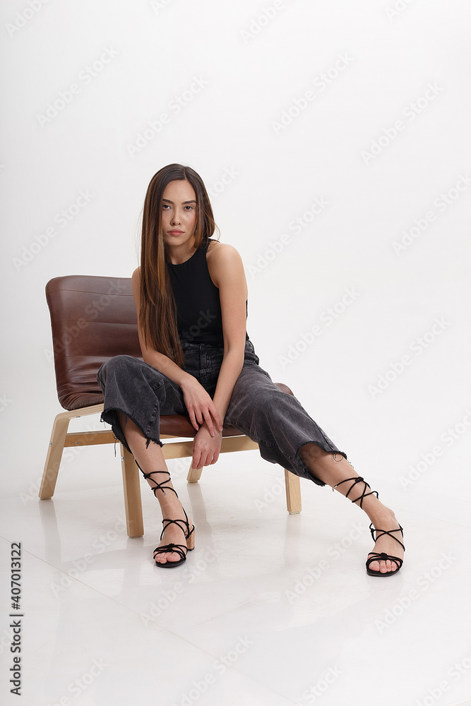 portrait of young attractive asian woman with long brown hair in black clothes, isolated on white studio background. skinny pretty female sitting on chair on cyclorama. model tests of beautiful lady portrait of young attractive asian woman with long brown hair in black clothes, isolated on white studio background. skinny pretty female sitting on chair on cyclorama. model tests of beautiful lady