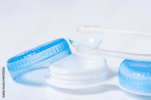 Soft contact lenses with solution, container and tweezers on white background with place for text. Macro photography