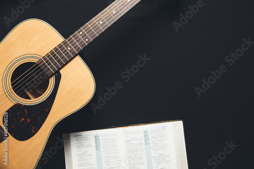 A guitar and an open bible on a black background